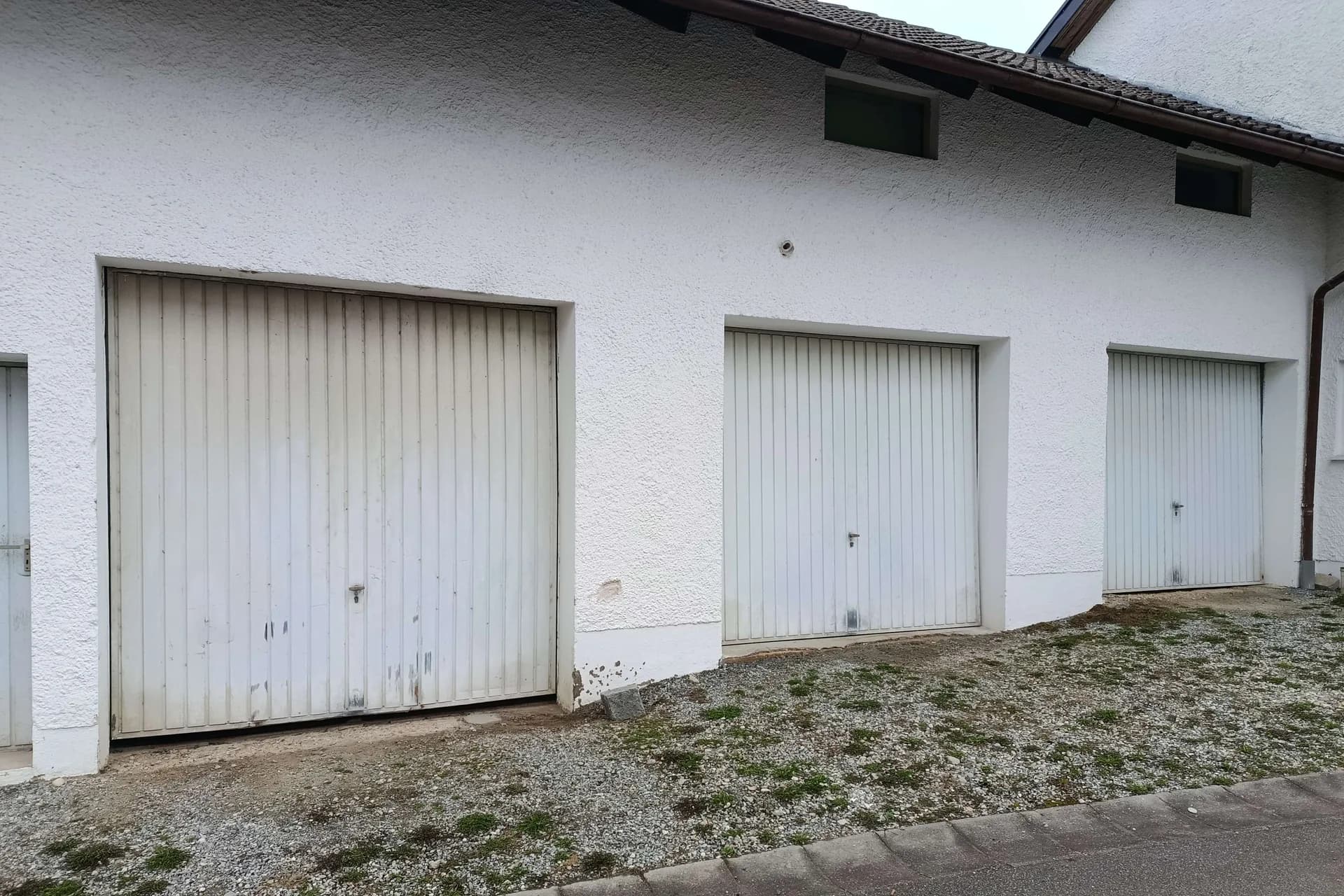 Drei ältere, weiße Garagentore an der Garage.
