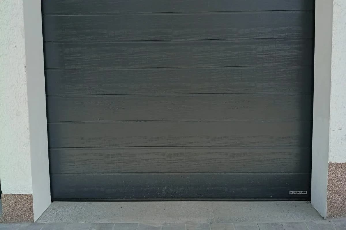 Neues dunkles Hörmann-Garagentor mit verputzter Laibung und saniertem Schwellenbereich aus Granit.