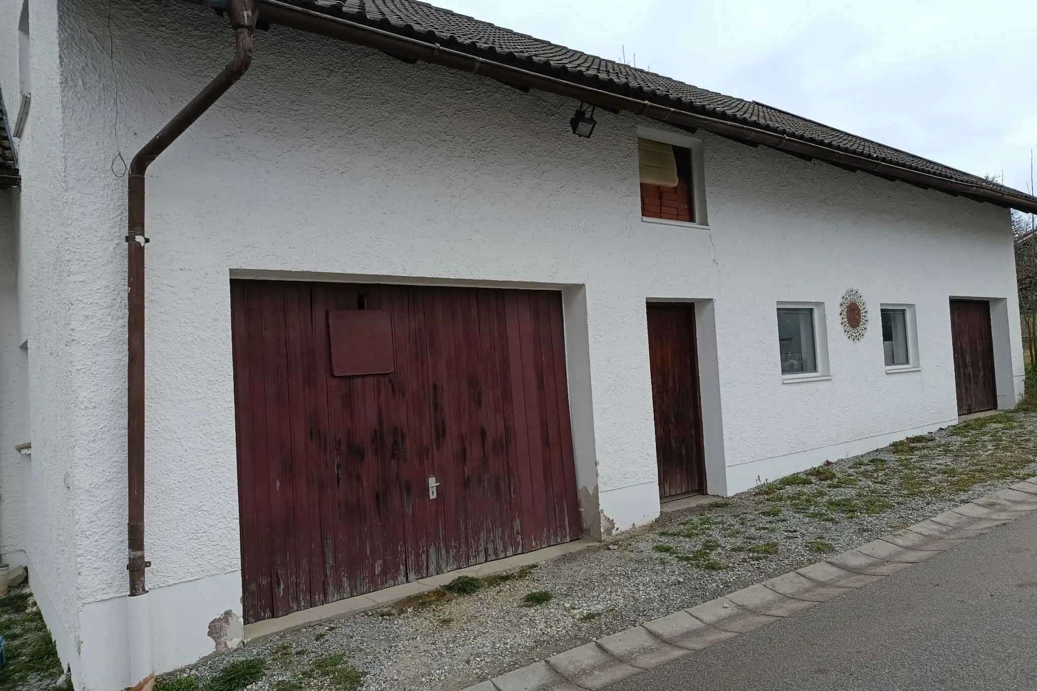 Älteres Gebäude in Ruhstorf an der Rott mit altem Holztor, alter Türe und sanierungsbedürftigen Laibungsbereichen.